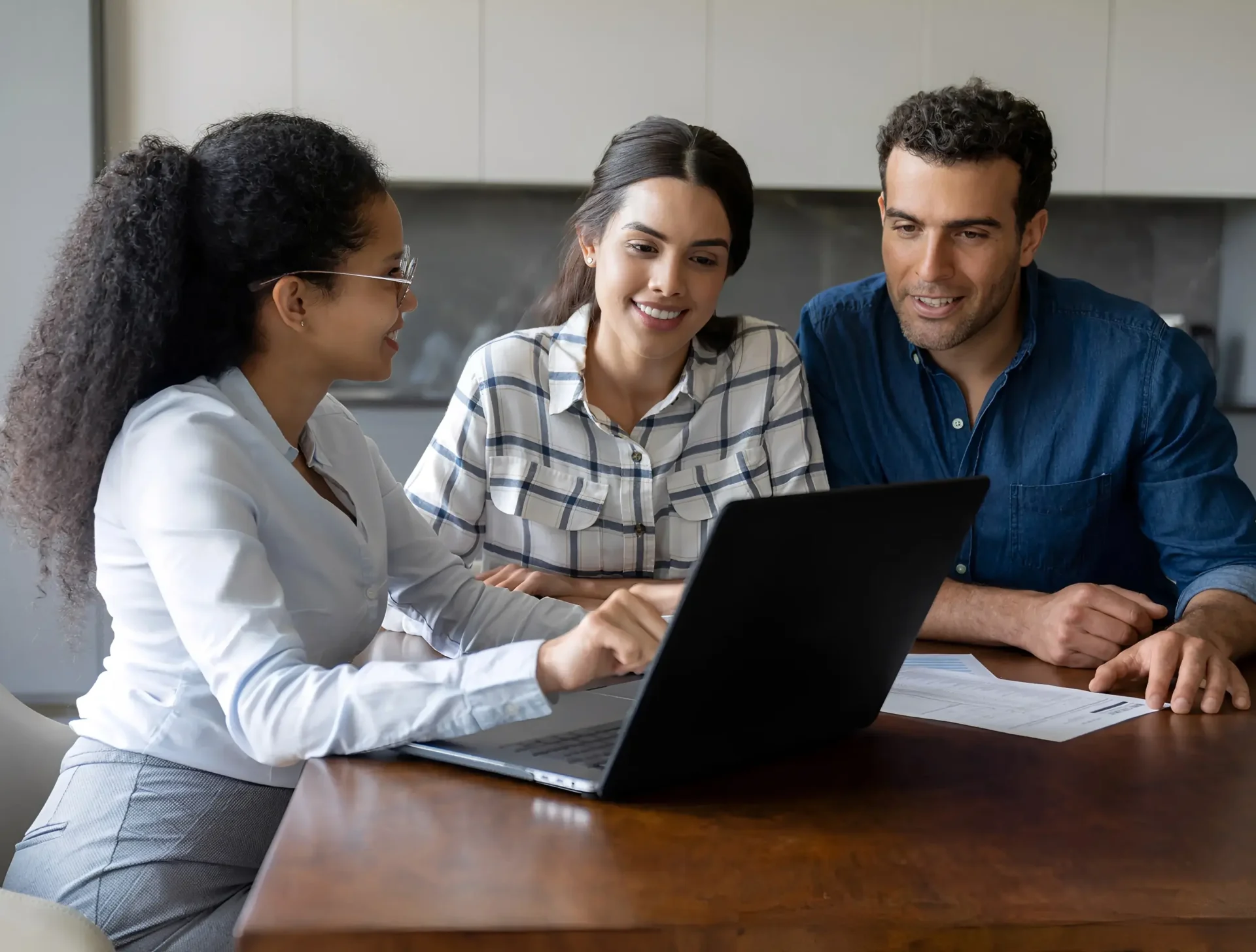 Three people discussing work at laptop.