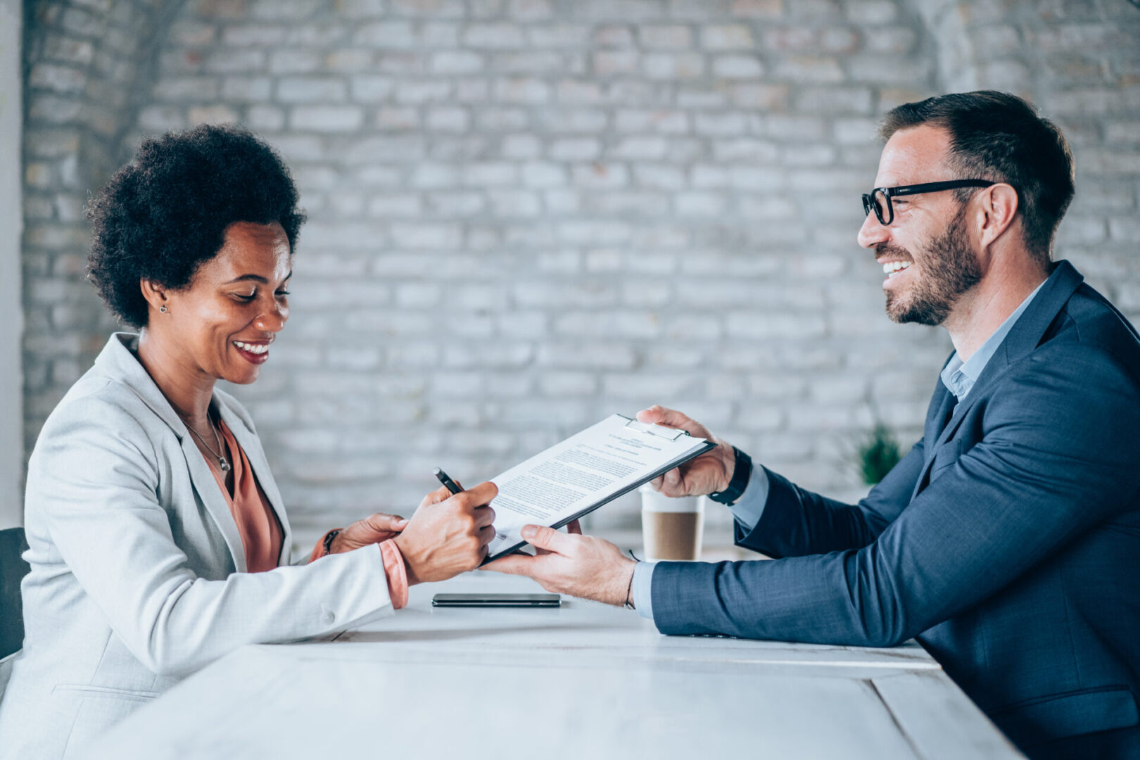 Two professionals exchanging a document, smiling.