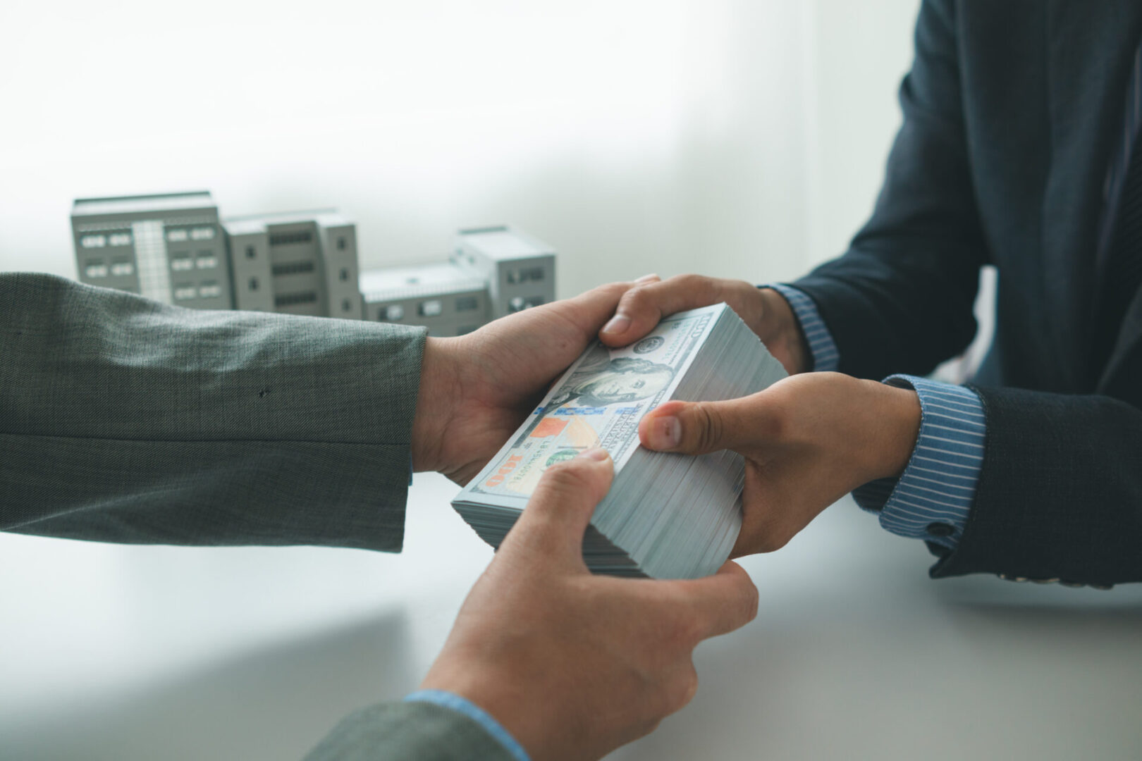 Two people exchanging a stack of money.