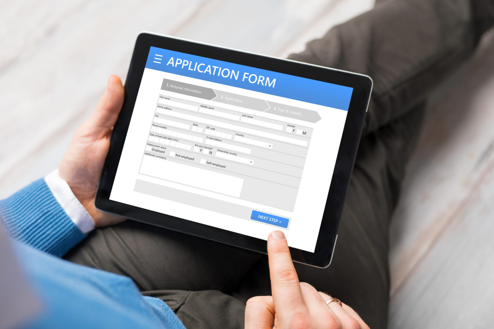 Person filling online application form on tablet.