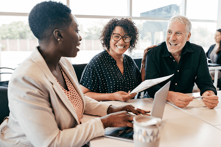 Three people smiling during a meeting.