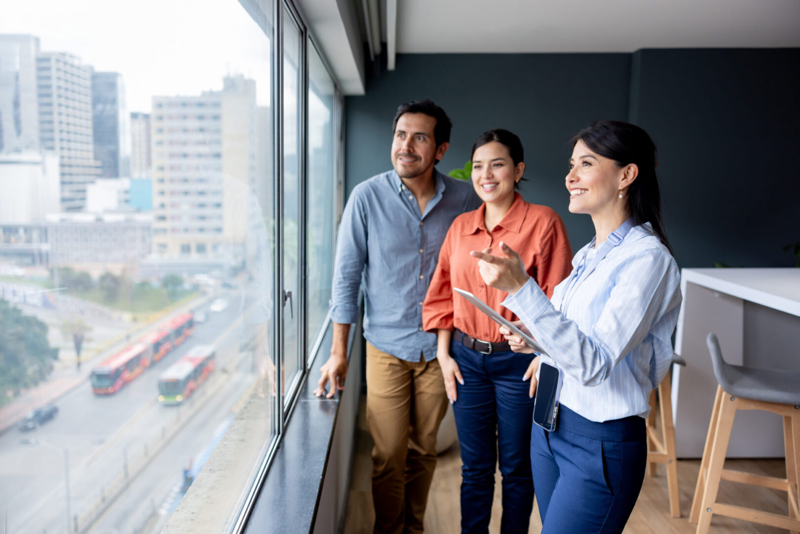 Commercial real estate agent showing an office to a couple of business people and pointing at the view through the window